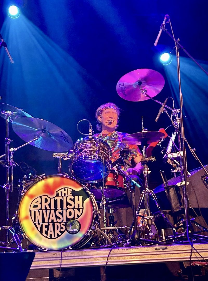 David Hall singing on a headset mic behind the tie-dye British Invasion Years drum kit