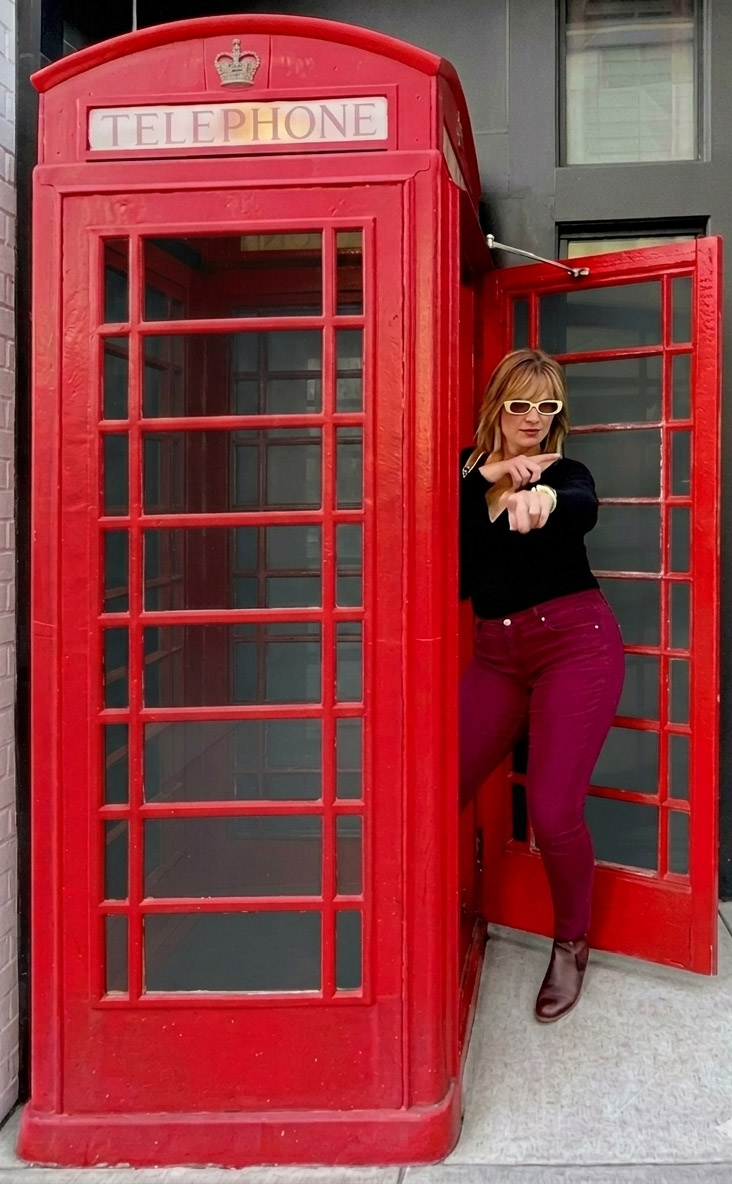 Rachel Hill of Blue Raven Entertainment leaning out of a red London telephone box